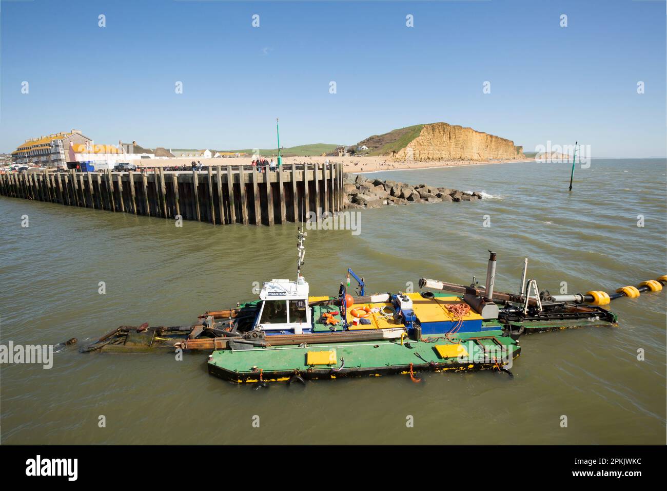 Un bateau de dragage en travaux dans le port de West Bay enlève le sable et les sédiments qui se sont accumulés au cours de l'hiver. West Bay Dorset Angleterre GB Banque D'Images