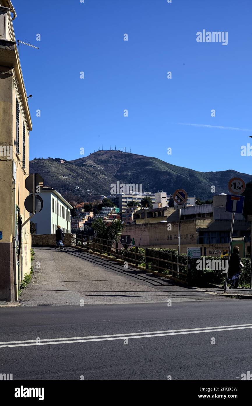 Avenue dans une ville italienne à côté d'une crête de montagne par une journée ensoleillée à midi Banque D'Images