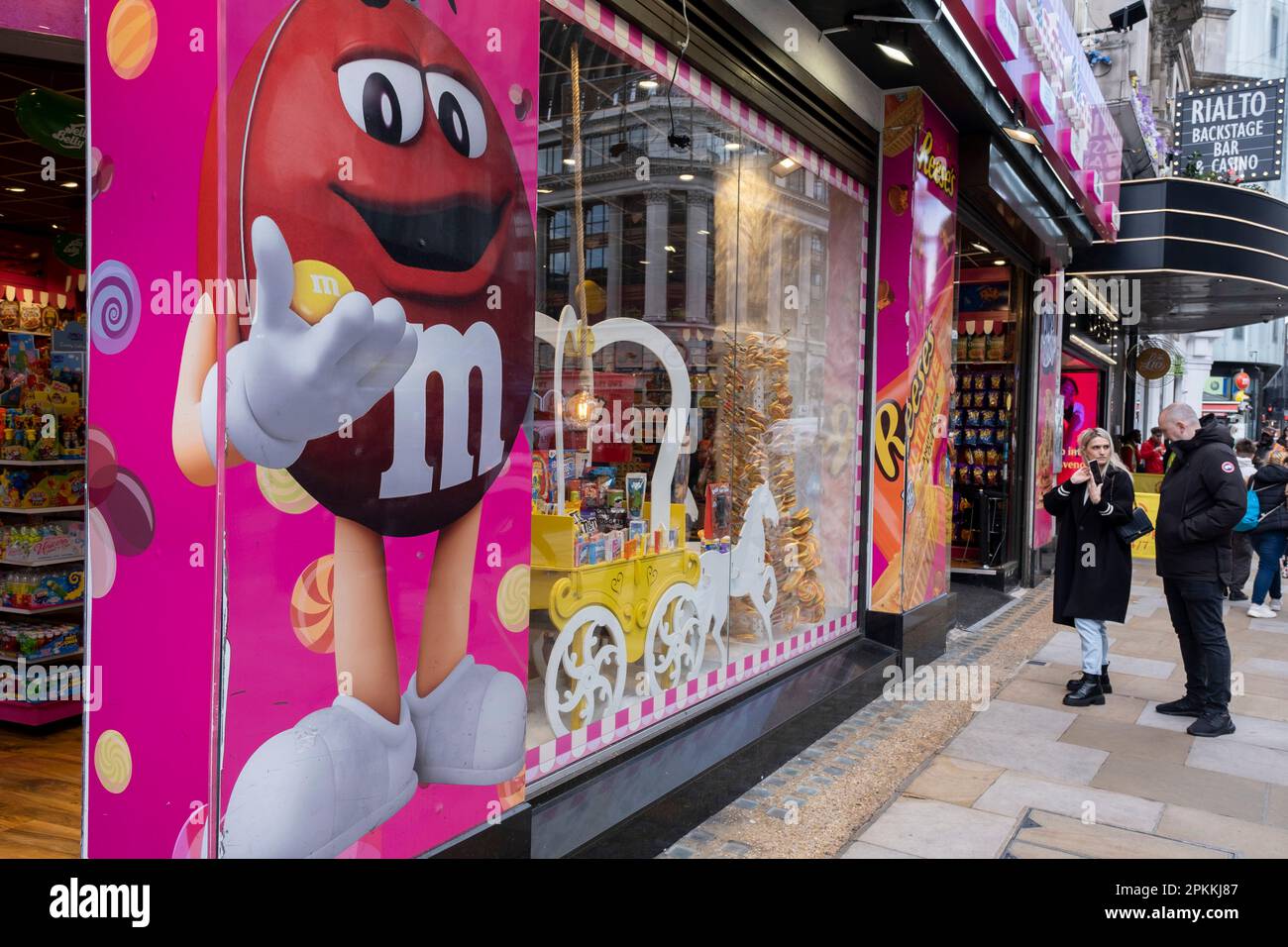Les gens marchent devant l'American Candy Shop avec la décoration de  caractère M&Ms à Leicester Square le 30th mars 2023 à Londres, au  Royaume-Uni. Il y a maintenant neuf méga magasins de