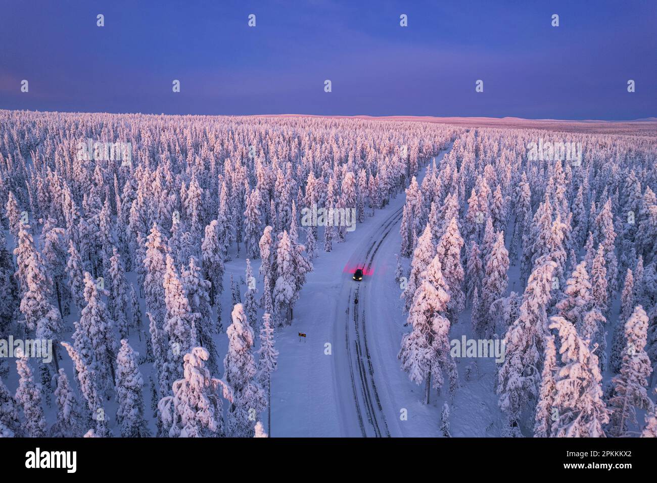 Vue aérienne d'une voiture traversant la forêt d'hiver couverte de neige à l'aube, Akaslompolo, Kolari, parc national de Pallas-Yllastunturi Banque D'Images