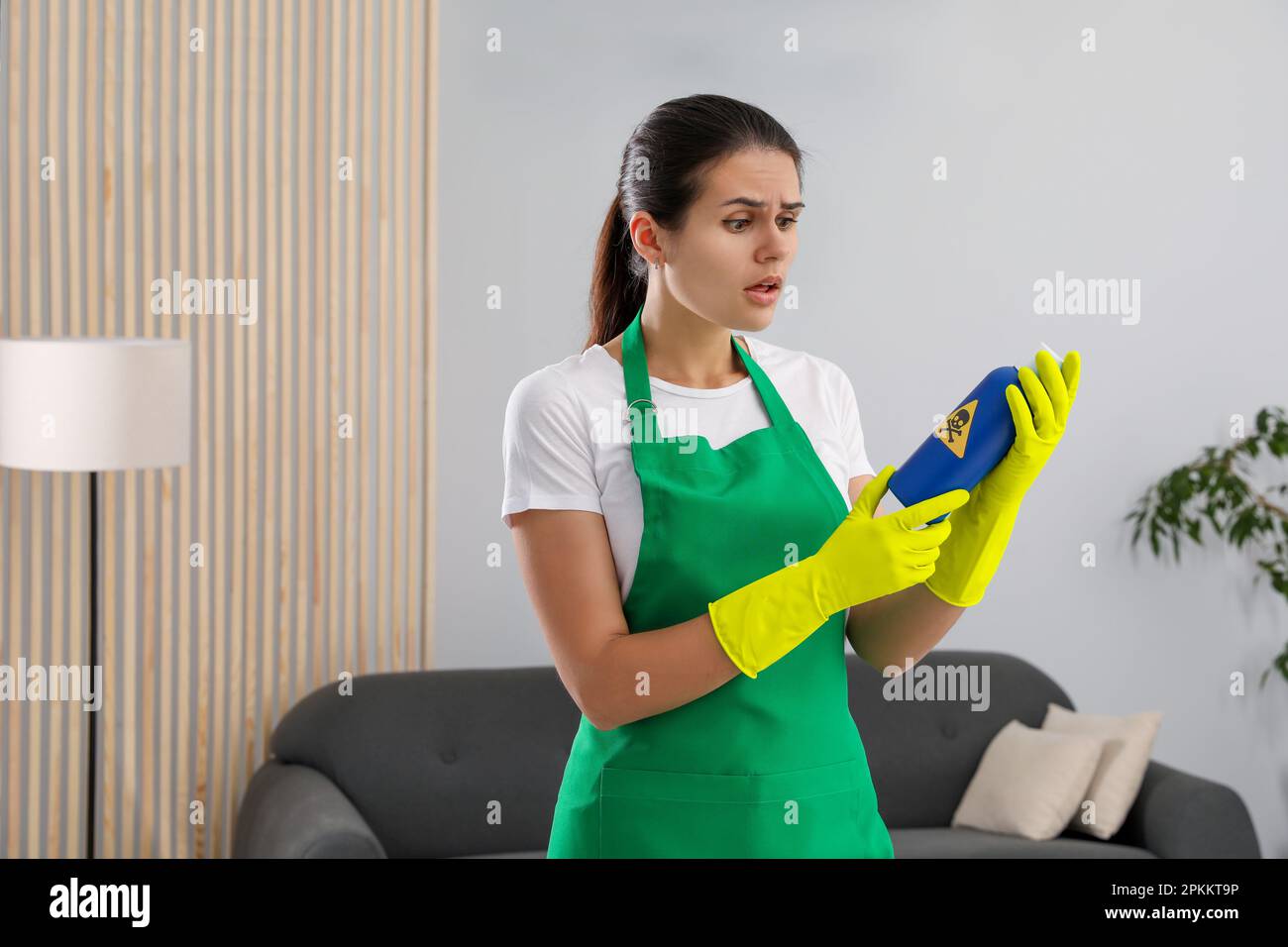 Femme regardant une bouteille de produit chimique toxique domestique avec un panneau d'avertissement à l'intérieur Banque D'Images