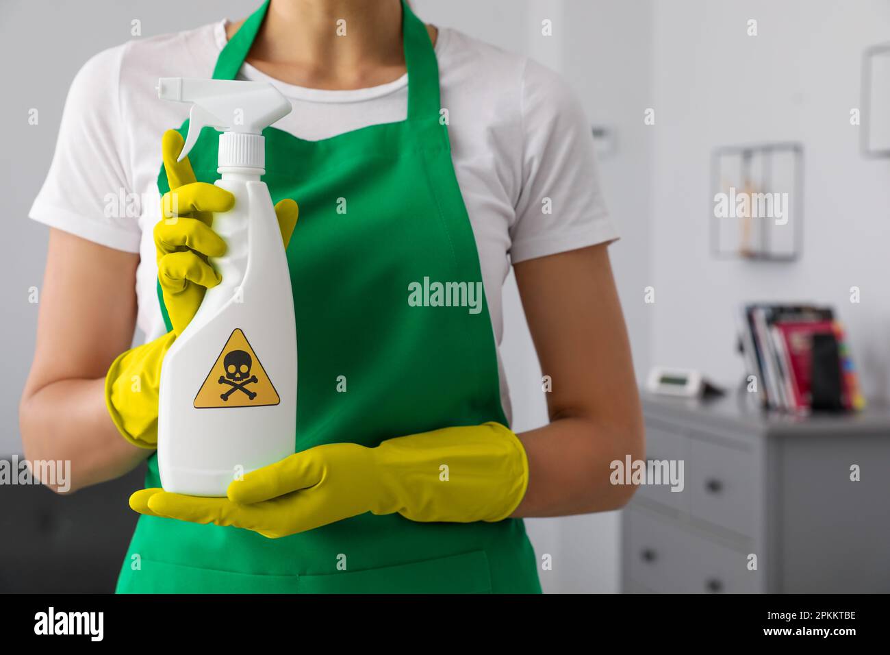 Femme présentant un spray chimique domestique toxique avec un panneau d'avertissement, gros plan Banque D'Images