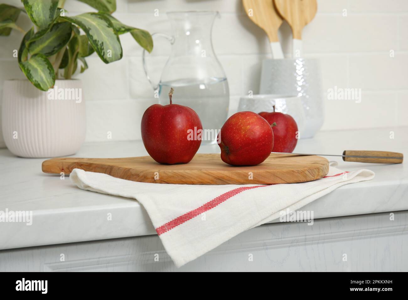 Une serviette propre et une planche en bois avec des pommes mûres sur le comptoir de la cuisine Banque D'Images