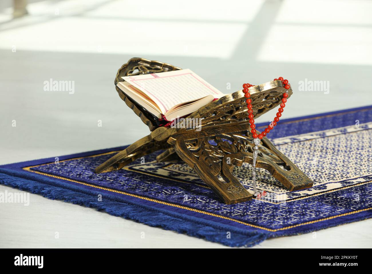 Rehal avec Quran ouvert et Misbaha sur tapis de prière musulman à l'intérieur Banque D'Images