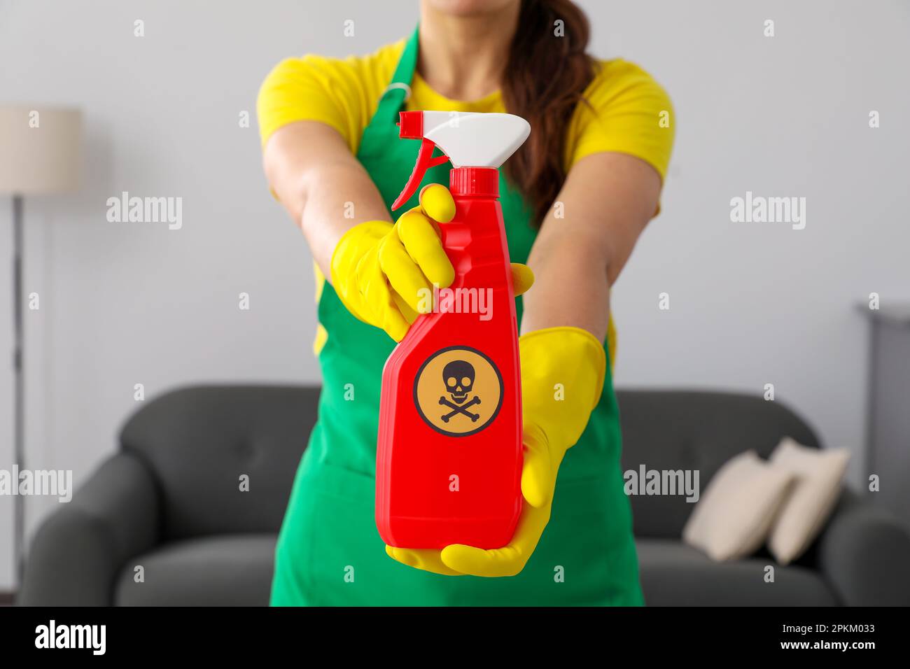 Femme montrant une bouteille de produit chimique toxique domestique avec un panneau d'avertissement, gros plan Banque D'Images