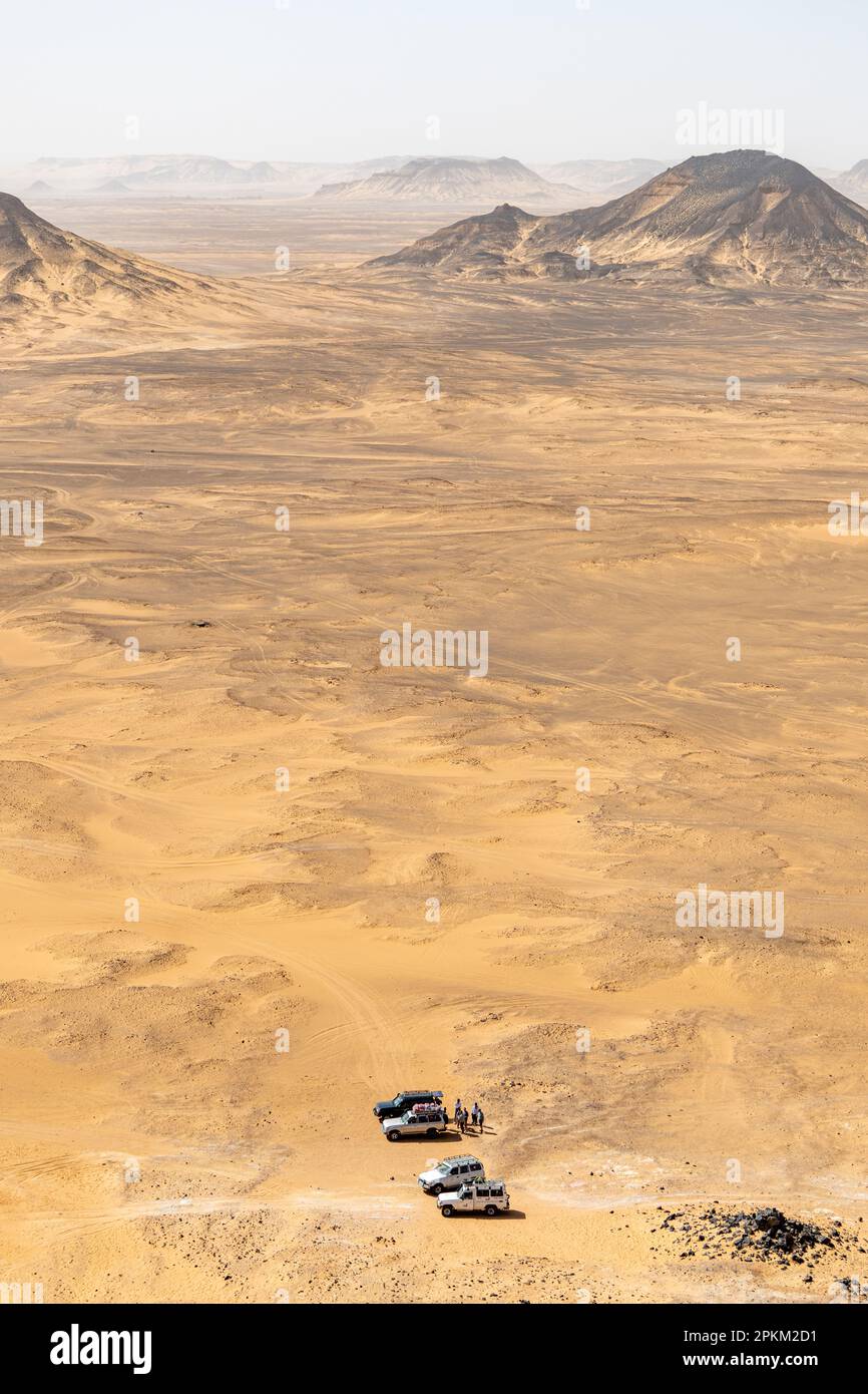 Jeeps garés à la base d'un basalte monte sur un plateau au désert noir en Égypte Banque D'Images