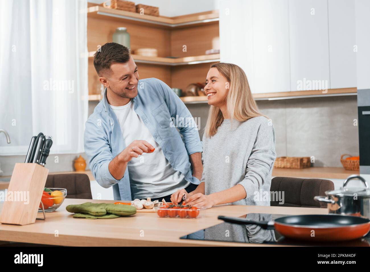 S'entraider. Couple préparant la nourriture à la maison sur la cuisine moderne. Banque D'Images