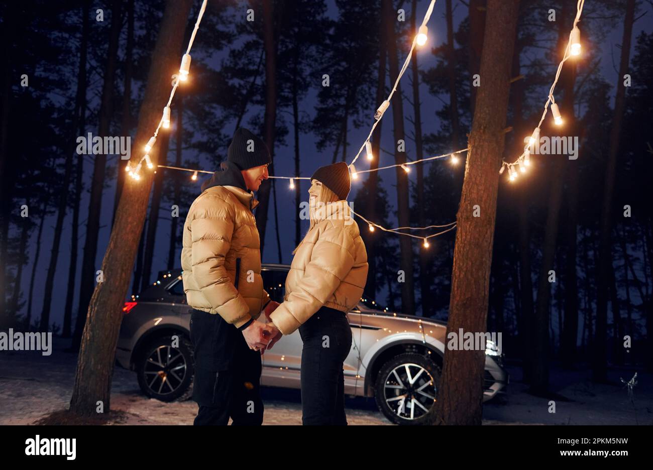 En tenant par les mains. Couple debout dans la forêt et célébrant le nouvel an. Banque D'Images