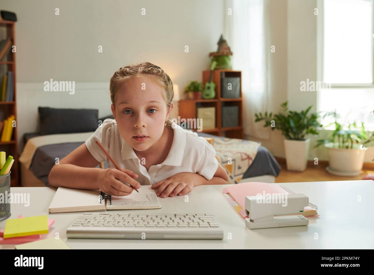 Une écolière fait ses devoirs à son bureau dans sa chambre Banque D'Images