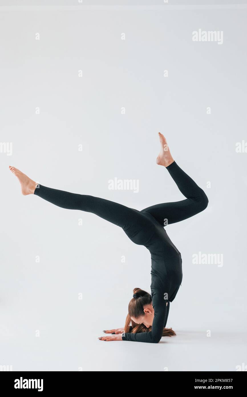 Pratiquez la routine. Jeune femme en vêtements de sport faisant de la gymnastique à l'intérieur. Banque D'Images