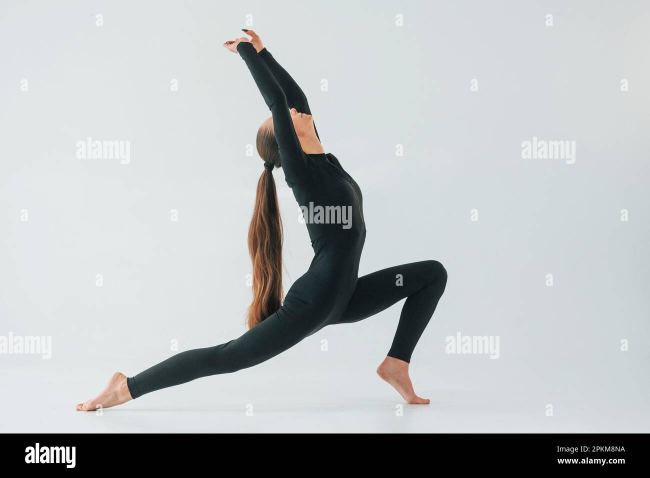 Personne en bonne santé. Jeune femme en vêtements de sport faisant de la gymnastique à l'intérieur. Banque D'Images
