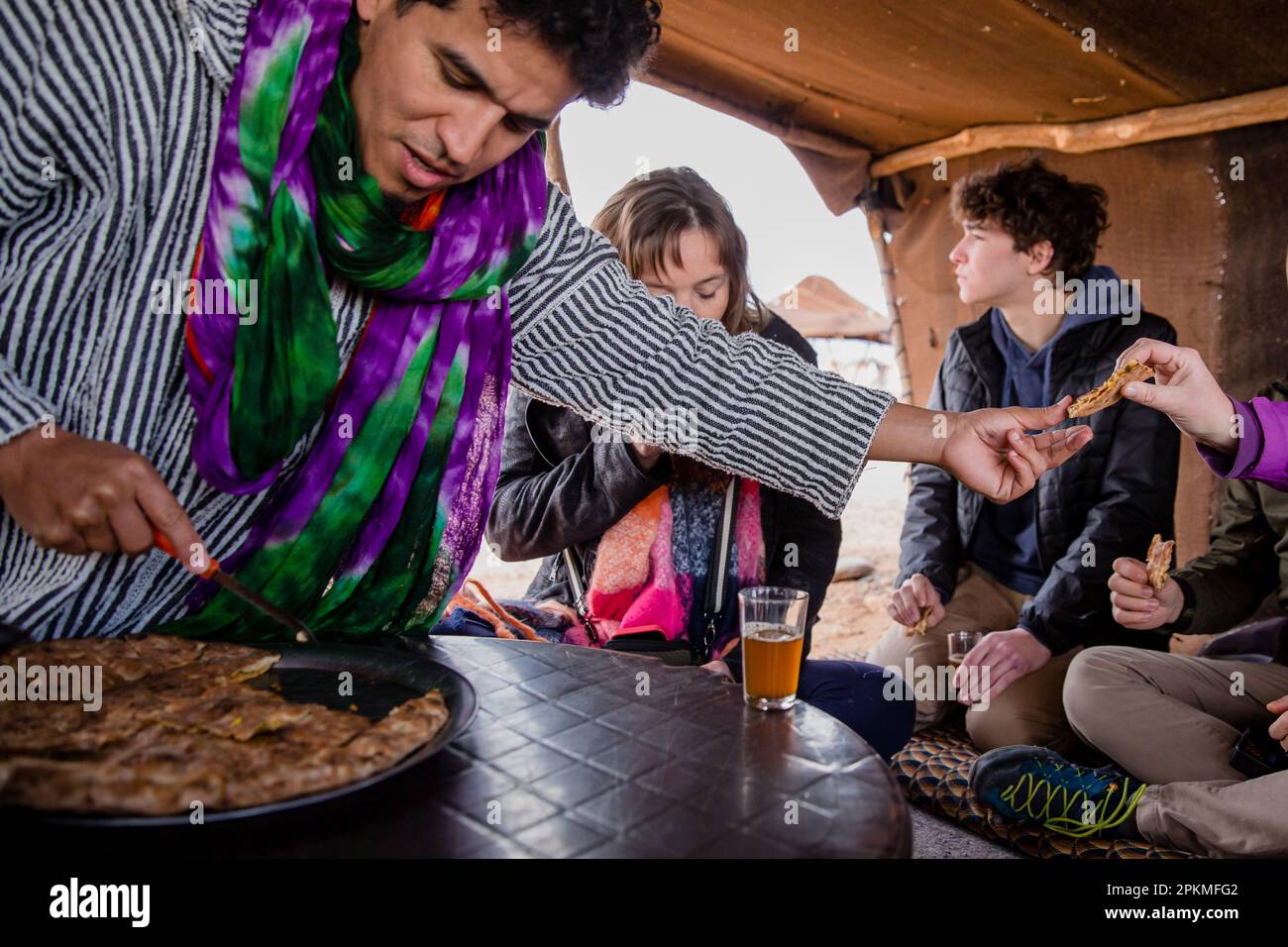 Un homme marocain passe des morceaux de pizza berbère à un touriste Banque D'Images