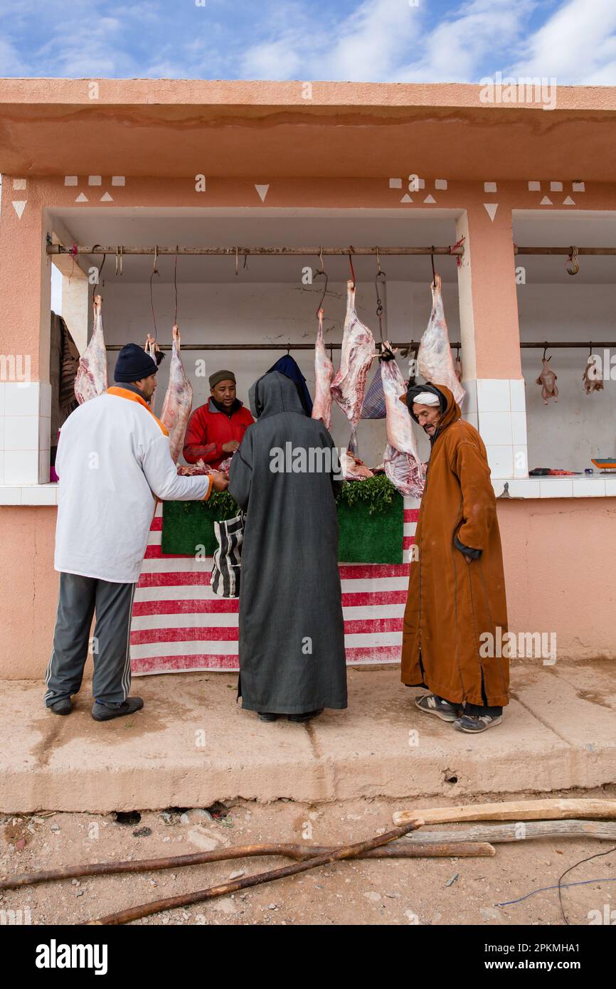 Des hommes marocains se réunissent à un stand de boucher dans un marché berbère Banque D'Images