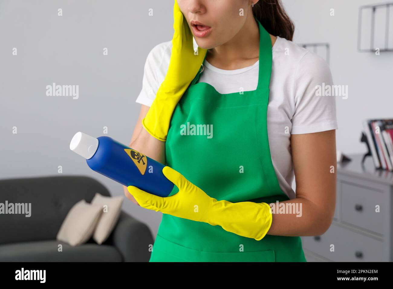 Femme regardant une bouteille de produit chimique toxique domestique avec un panneau d'avertissement, gros plan Banque D'Images