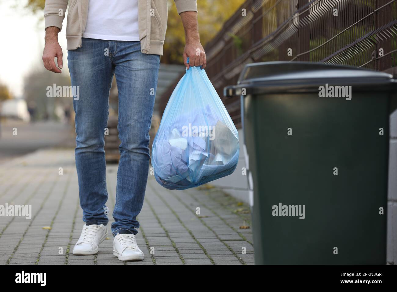 Homme transportant un sac poubelle vers un bac de recyclage à l'extérieur,  en gros plan Photo Stock - Alamy