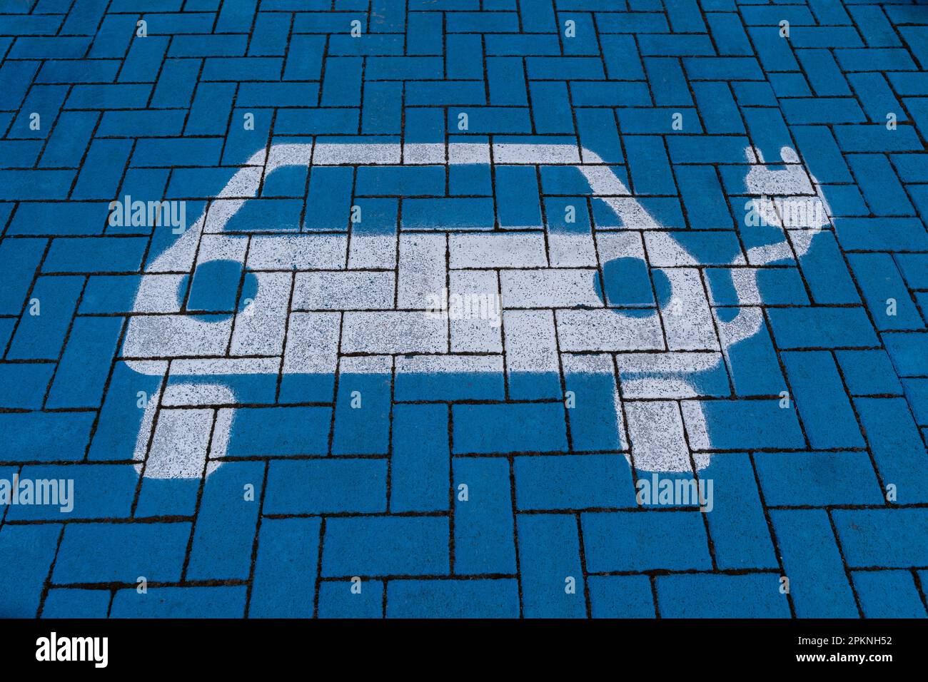 Symbole de voiture électrique blanc sur un sol bleu dans une station de charge Banque D'Images Symbole de voiture électrique blanc sur un sol bleu dans une station de charge Banque D'Images