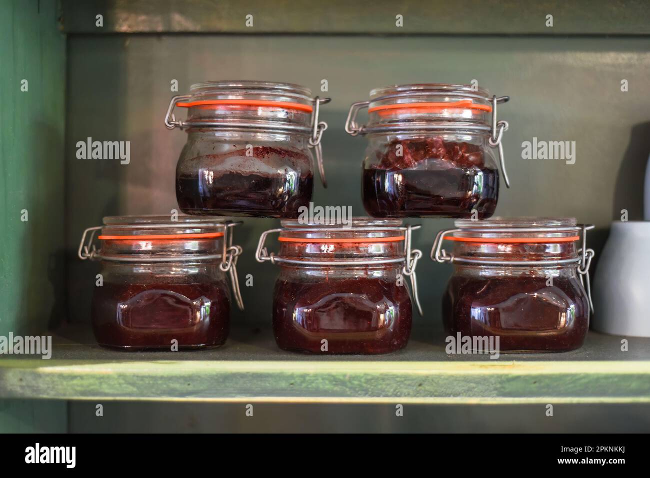 Pots avec confiture maison sur une étagère en bois dans une rangée Banque D'Images