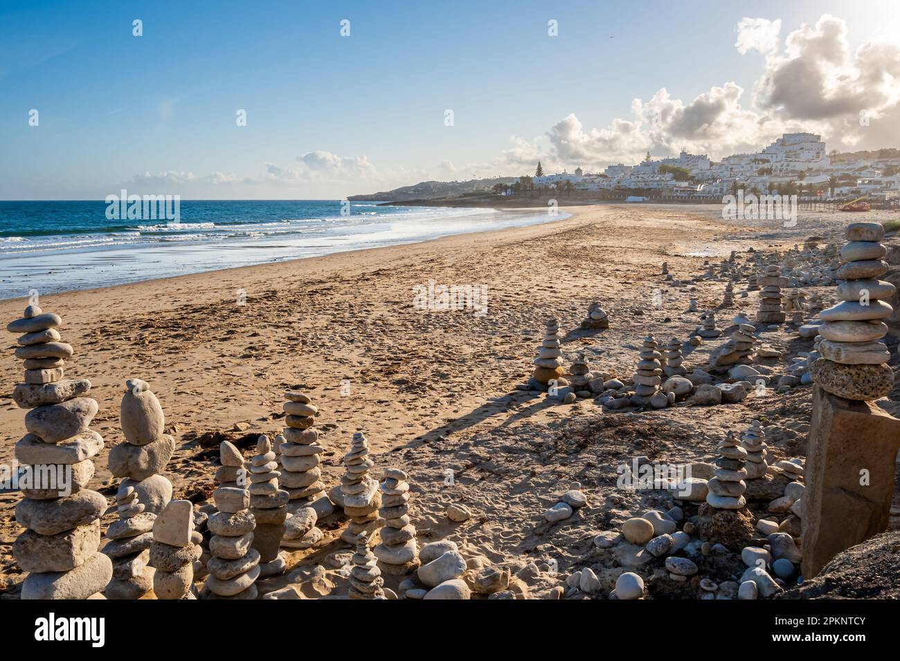 Tandis que la lumière du soleil du soir illumine la plage de Luz, des œuvres d'art hypnotiques en pierre attirent l'œil, créant une scène méditative. Banque D'Images