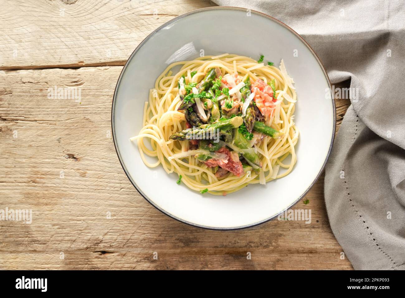 sauce végétale aux asperges vertes et tomates au parmesan et au persil, garnir de spaghetti dans une assiette sur une table en bois rustique, haut angle vie Banque D'Images