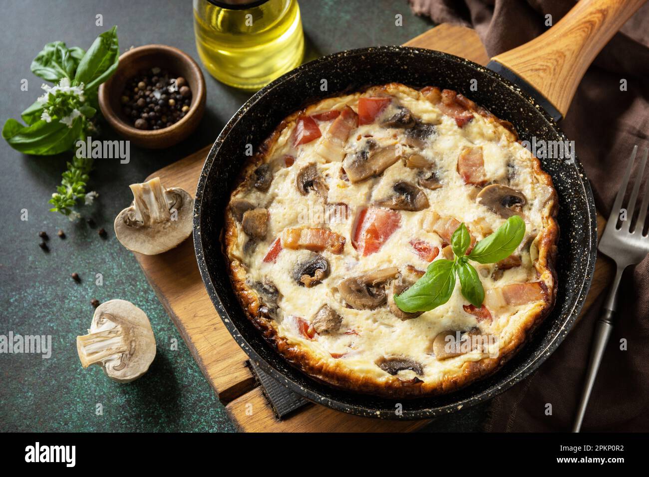 Omelette aux champignons et bacon sur une table en pierre sombre. Frittata est un plat de petit-déjeuner italien. Banque D'Images