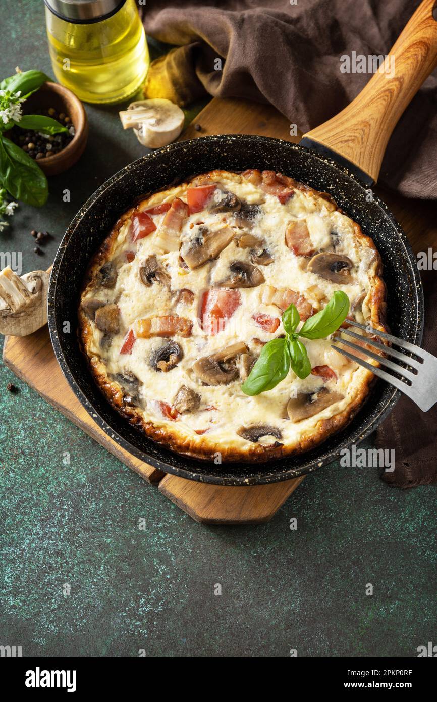Omelette aux champignons et bacon sur une table en pierre sombre. Frittata est un plat de petit-déjeuner italien. Copier l'espace. Banque D'Images