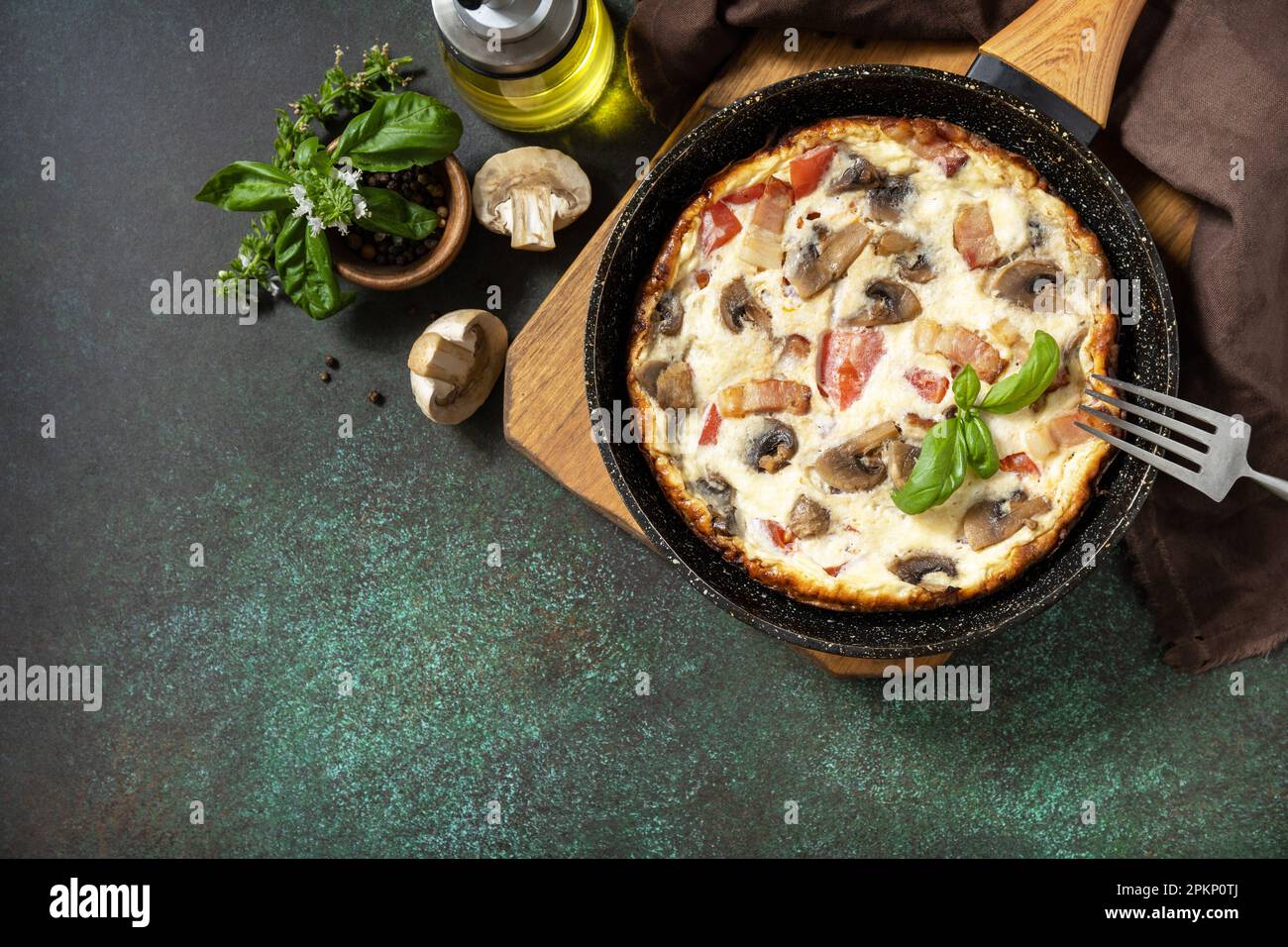Frittata est un plat de petit-déjeuner italien. Omelette aux champignons et bacon sur une table en pierre sombre. Vue de dessus. Copier l'espace. Banque D'Images