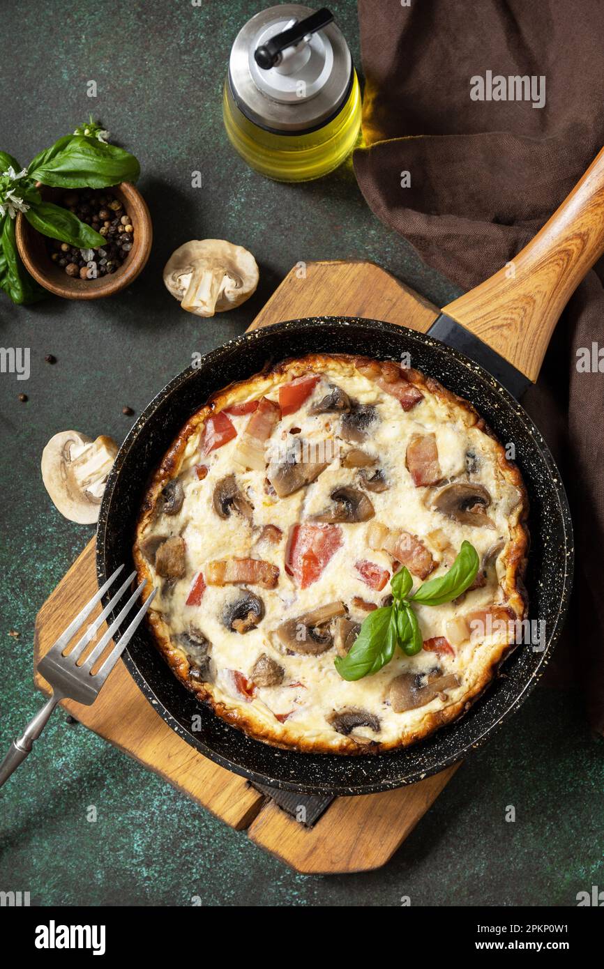 Omelette aux champignons et bacon sur une table en pierre sombre. Frittata est un plat de petit-déjeuner italien. Vue de dessus. Banque D'Images