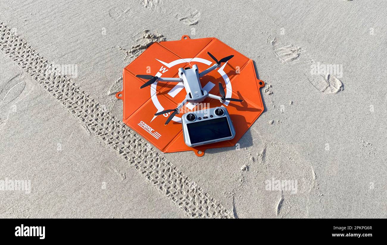 Fire Island, New York, Etats-Unis - 20 février 2023: DDJI mini pro 3 drone sur un plateau de décollage orange avec son contrôleur sur le sable à la plage. Banque D'Images