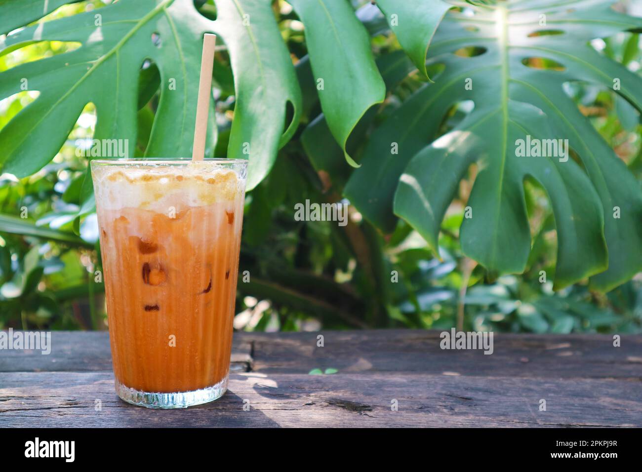 Verre de thé glacé thaïlandais appétissant isolé sur la table de jardin Banque D'Images
