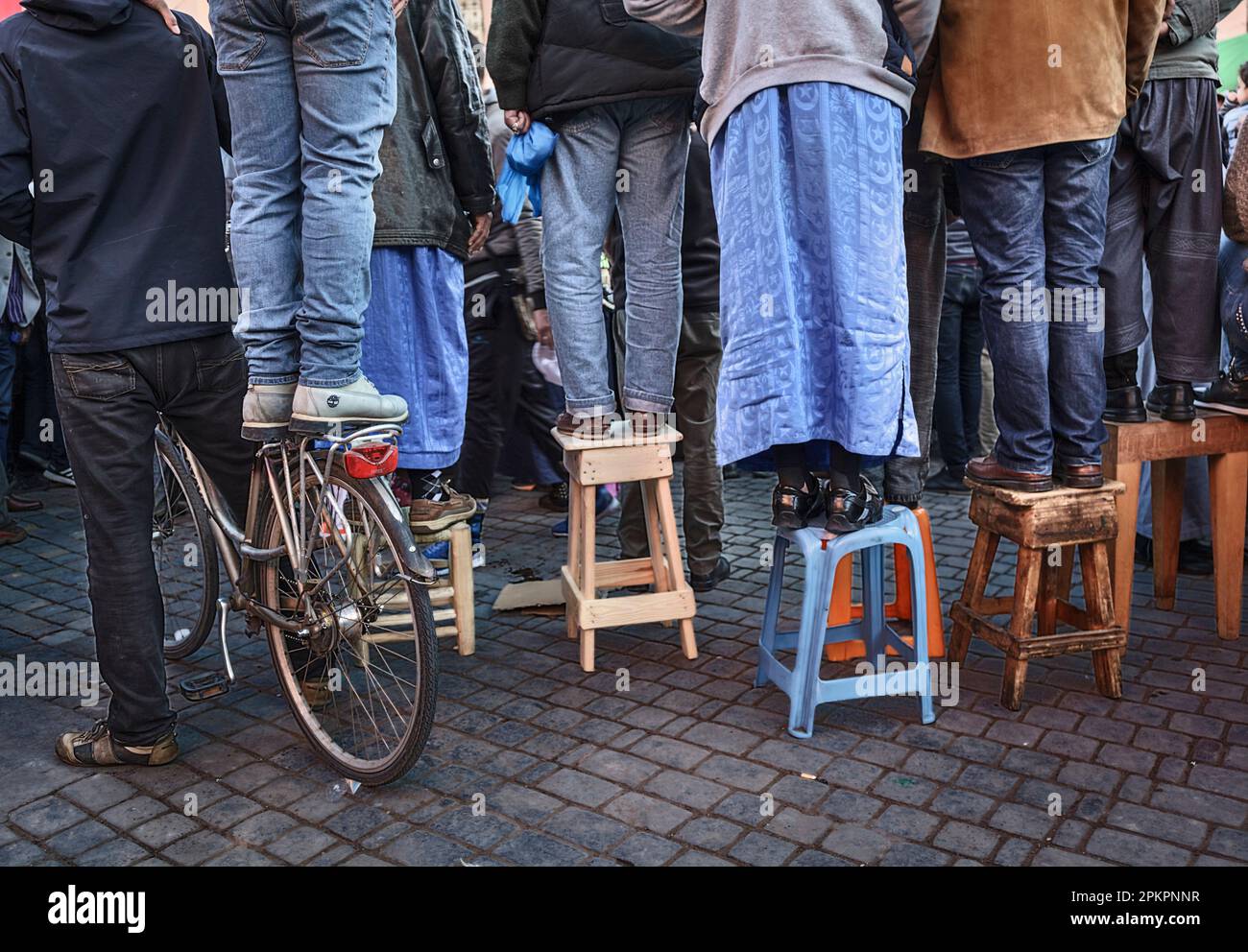 La position marocaine sur des chaises et un vélo pour avoir une vue sur la visite du roi Mohammed V1 aux bazars de la Médina de Marrakech. Banque D'Images