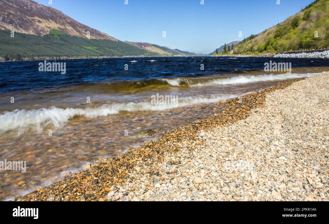 De petites vagues se brisent sur le rivage de galets du Loch Lochy dans les Highlands écossais Banque D'Images