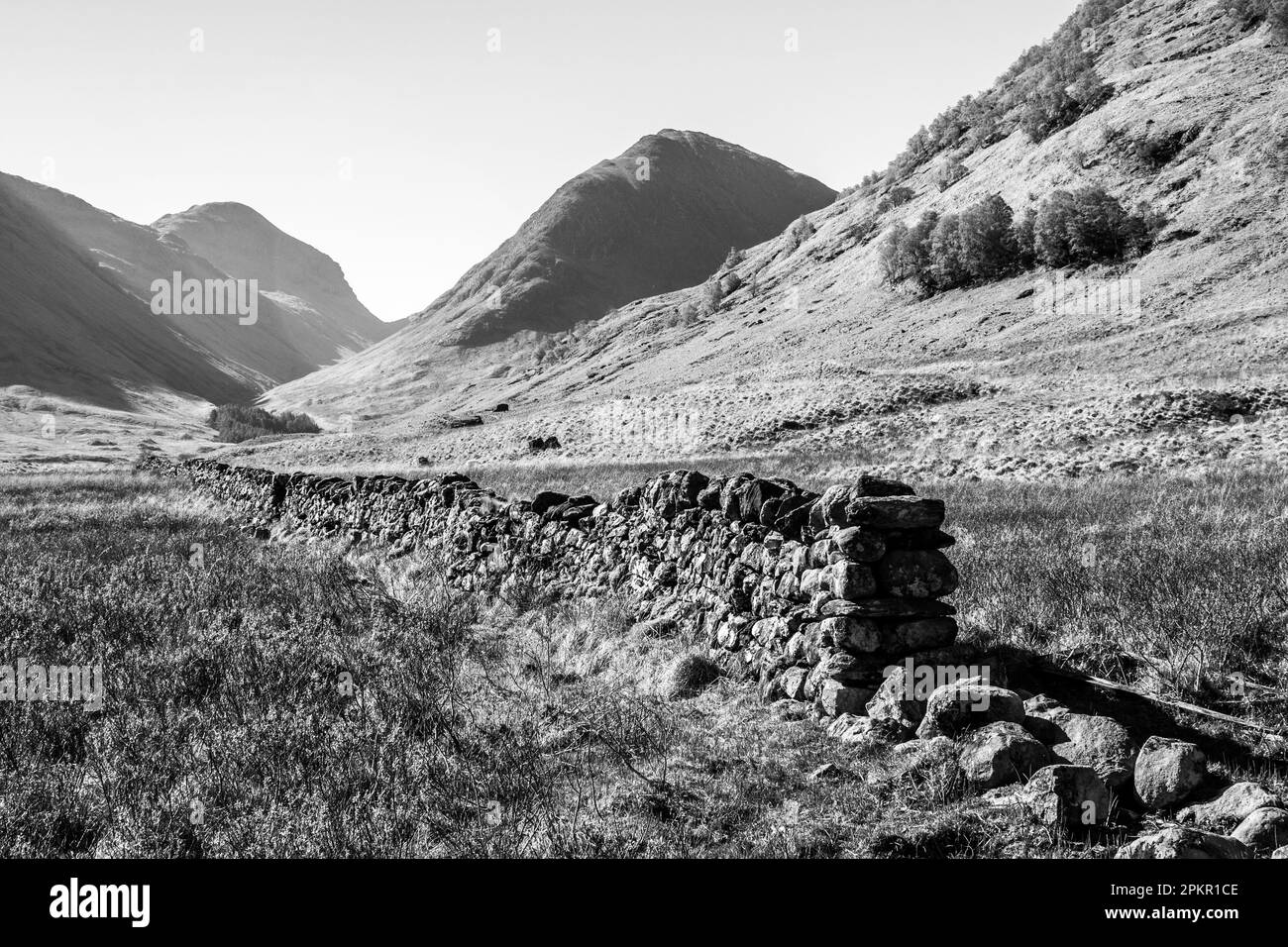 Vue en noir et blanc d'une cloison sèche en pierre menant à Glen COE, dans les Highlands écossais Banque D'Images