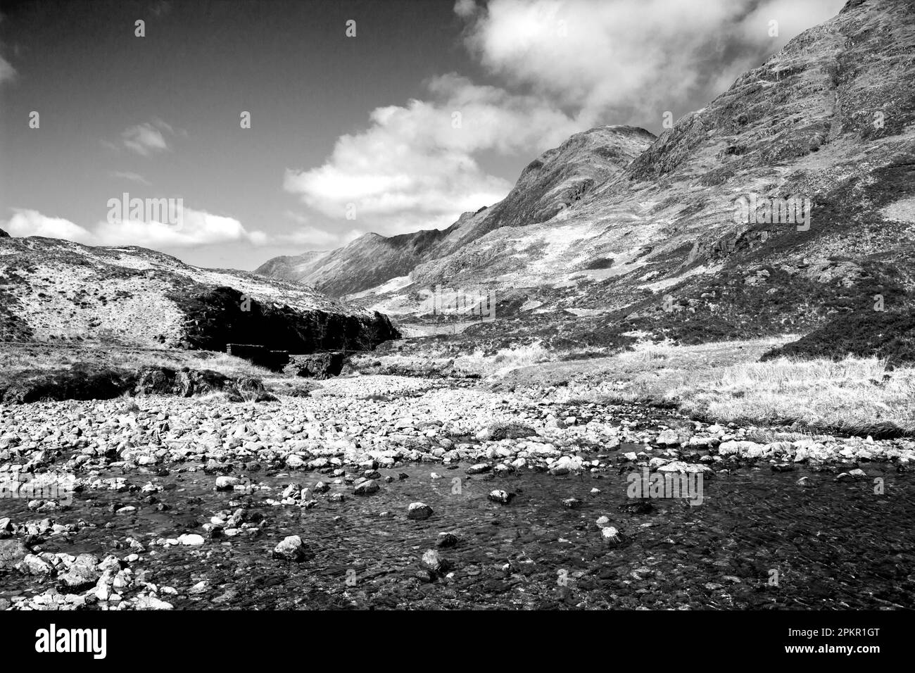 Un des nombreux ruisseaux de montagne qui s'écoulent à travers le paysage accidenté de Glen COE, dans les Highlands écossais, en noir et blanc Banque D'Images