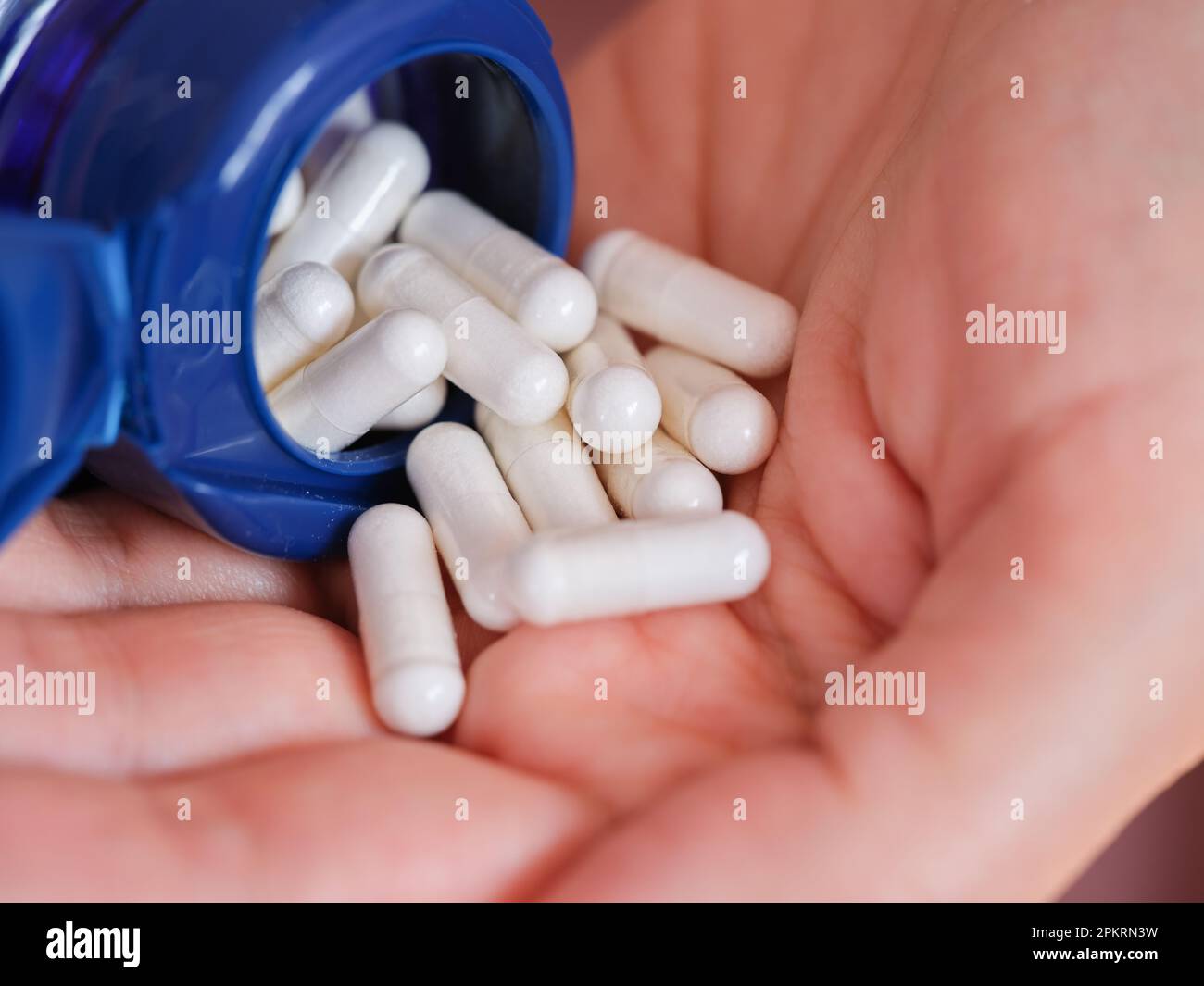 Une femme verse des capsules de diméthylaminoéthanol bitartrate (DMAE) d'une bouteille dans la paume de sa main. Gros plan. Banque D'Images