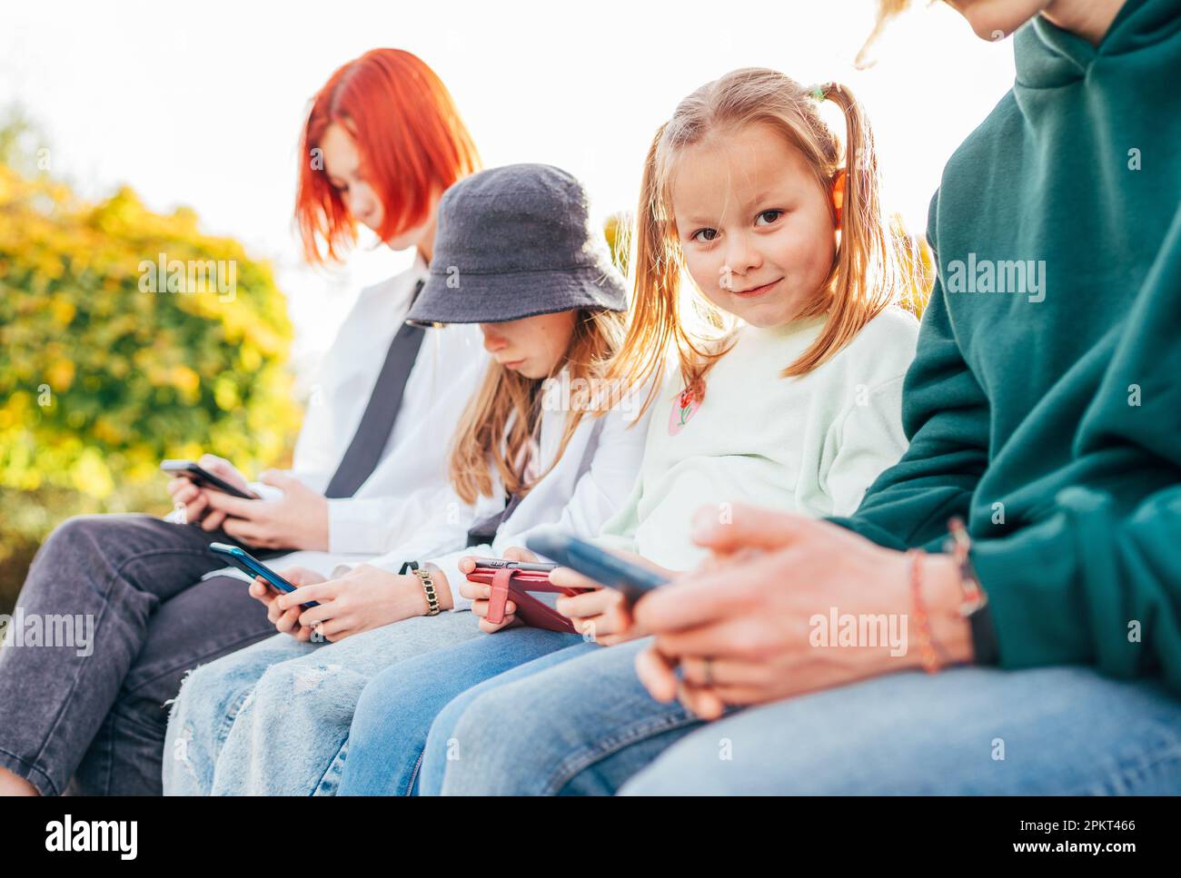 Petit joli portrait de fille avec sœurs filles enfants assis dans une rangée et la navigation de leurs appareils de smartphone. Un moment insouciant de jeune heure de teenhood et un moderne Banque D'Images