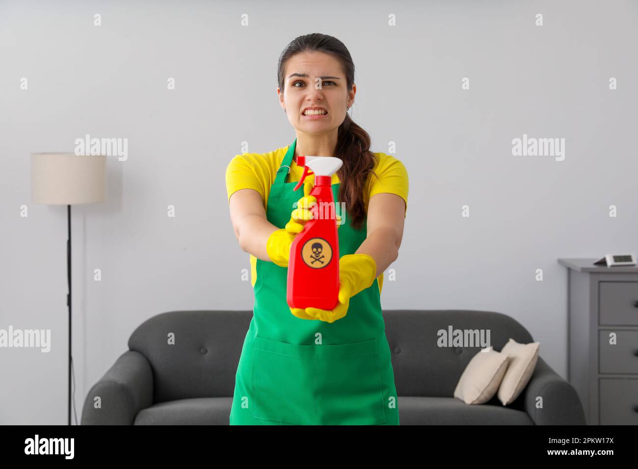 Femme montrant une bouteille de produit chimique toxique domestique avec un panneau d'avertissement à l'intérieur Banque D'Images