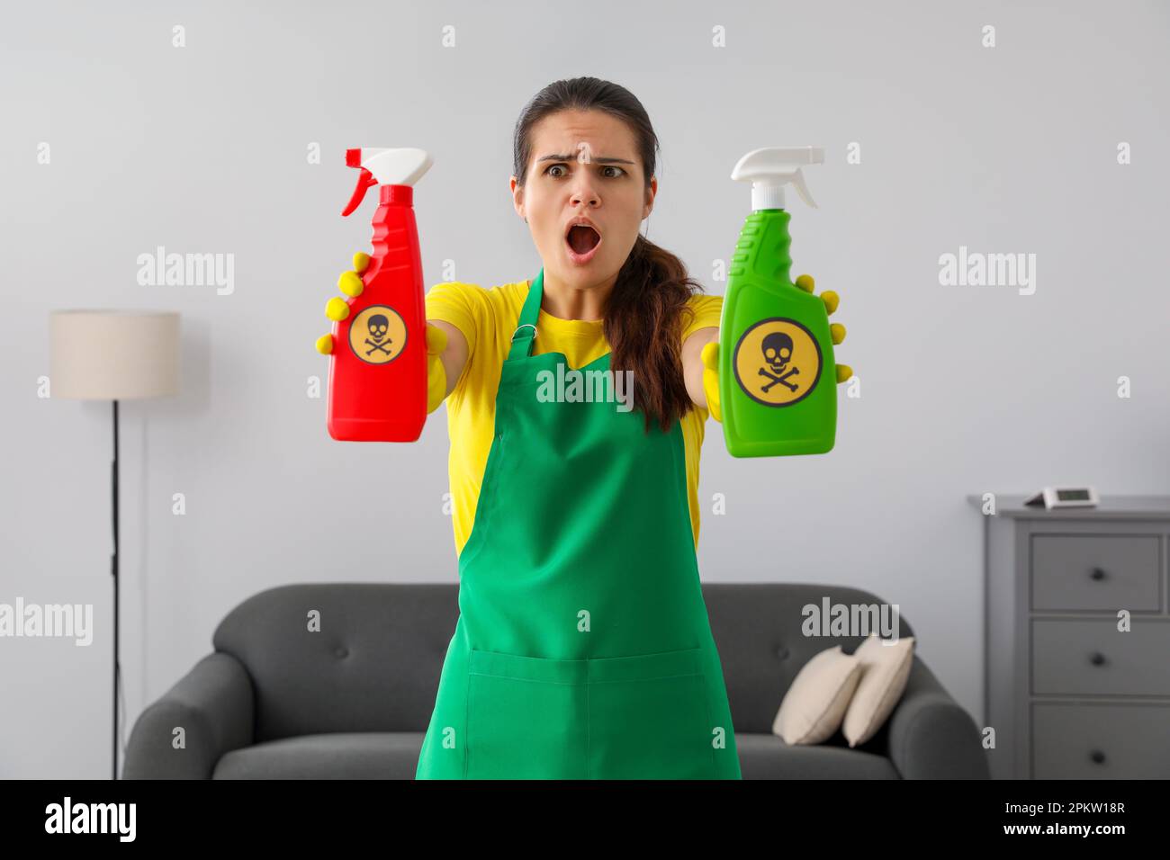 Femme montrant des bouteilles de produits chimiques toxiques domestiques avec des panneaux d'avertissement Banque D'Images