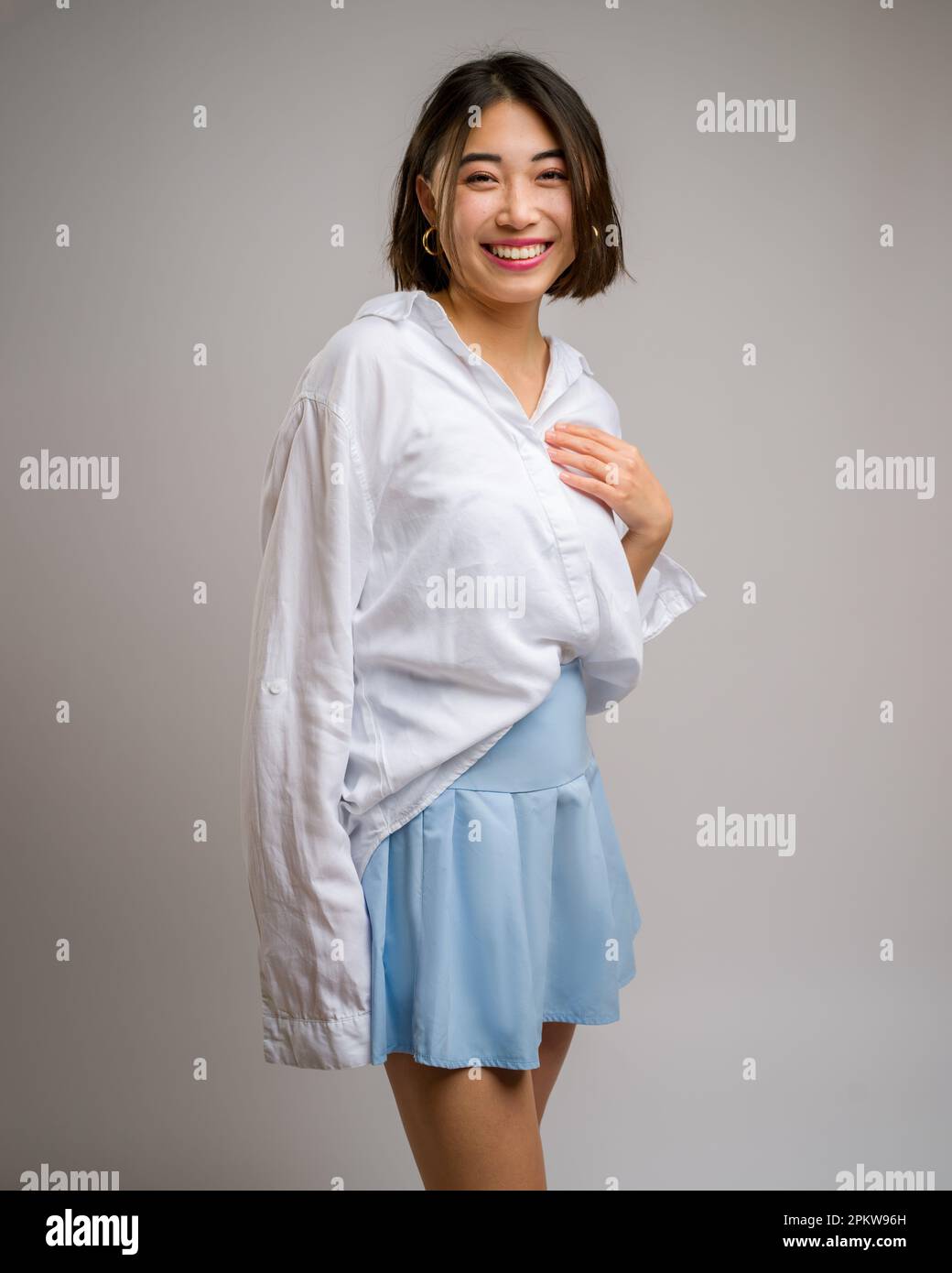 1/2 demi-corps Portrait de la jeune femme asiatique dans une jupe bleue courte et un chemisier blanc à manches longues | toile de fond blanche | heureux Banque D'Images