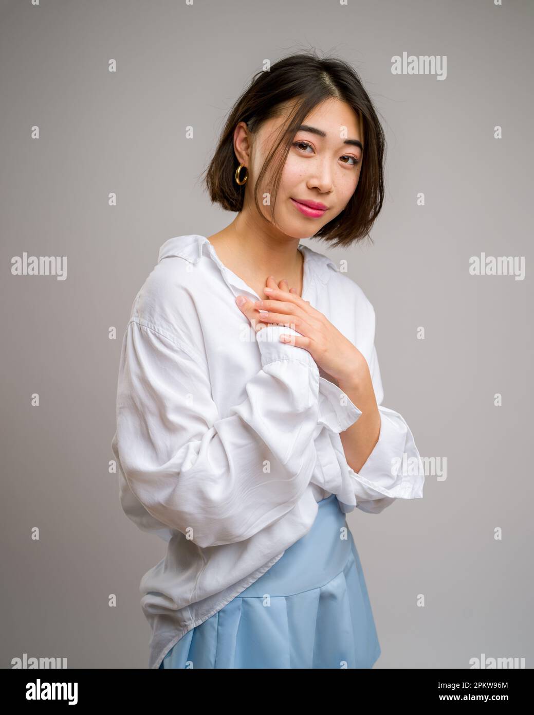 1/2 demi-corps Portrait de la jeune femme asiatique dans une jupe bleue courte et un chemisier blanc à manches longues | toile de fond blanche | heureux Banque D'Images