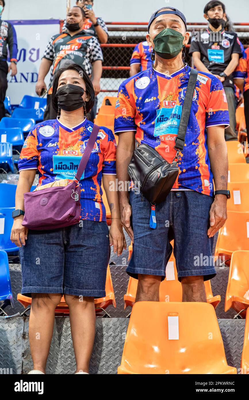 Les supporters et les spectateurs du Port F.C. se tenant pour l'hymne national avant le match de la ligue de football thaï au stade PAT, Khlong Toey, Bangkok, Thaïlande Banque D'Images