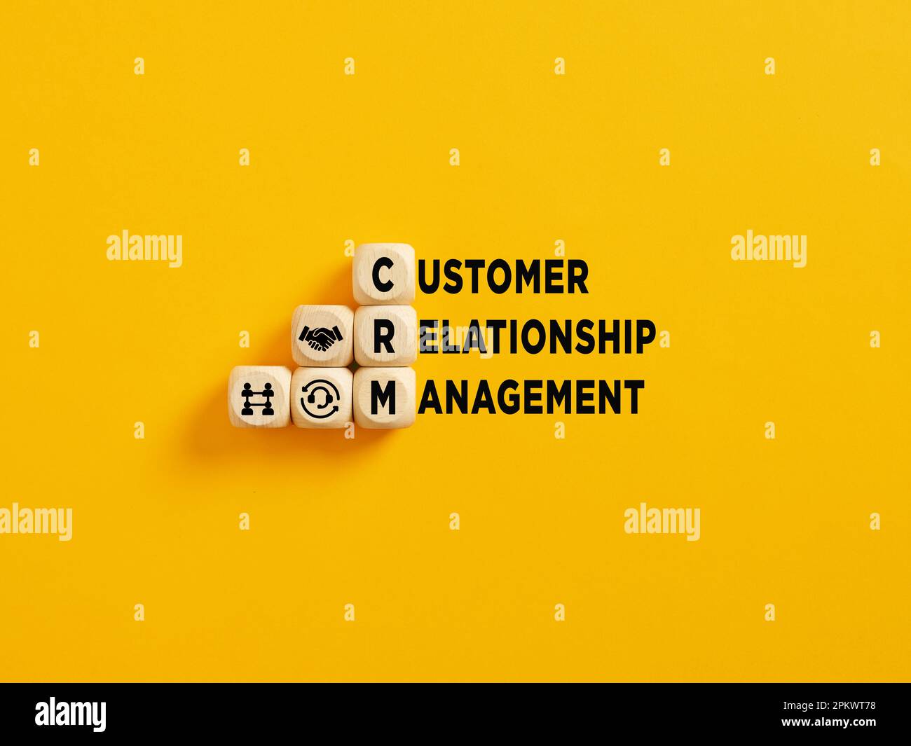 L'acronyme CRM et Customer Relationship Management text sur cubes en bois sur fond jaune. Banque D'Images