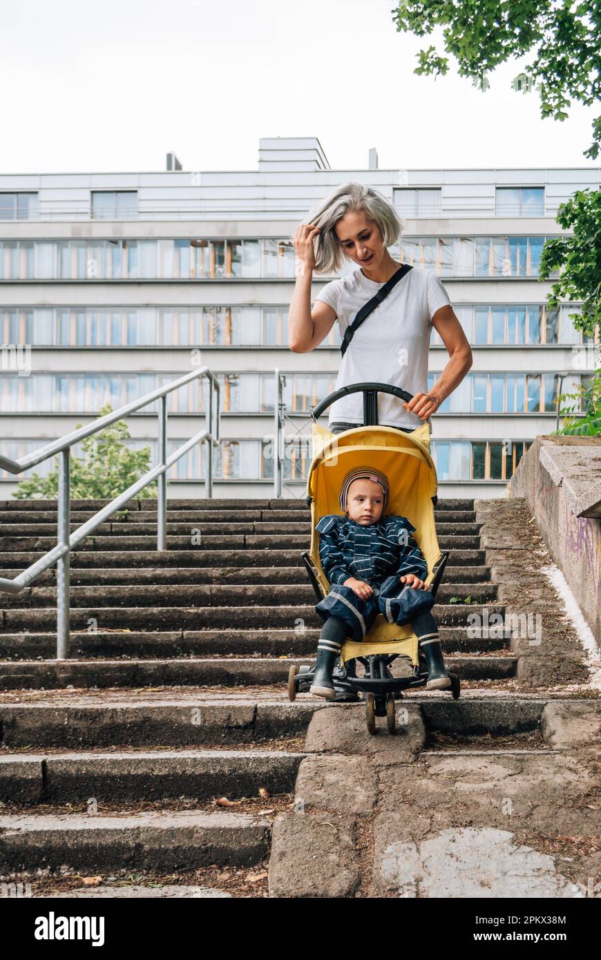 Une femme roule une poussette avec un enfant sur la rampe des escaliers Banque D'Images