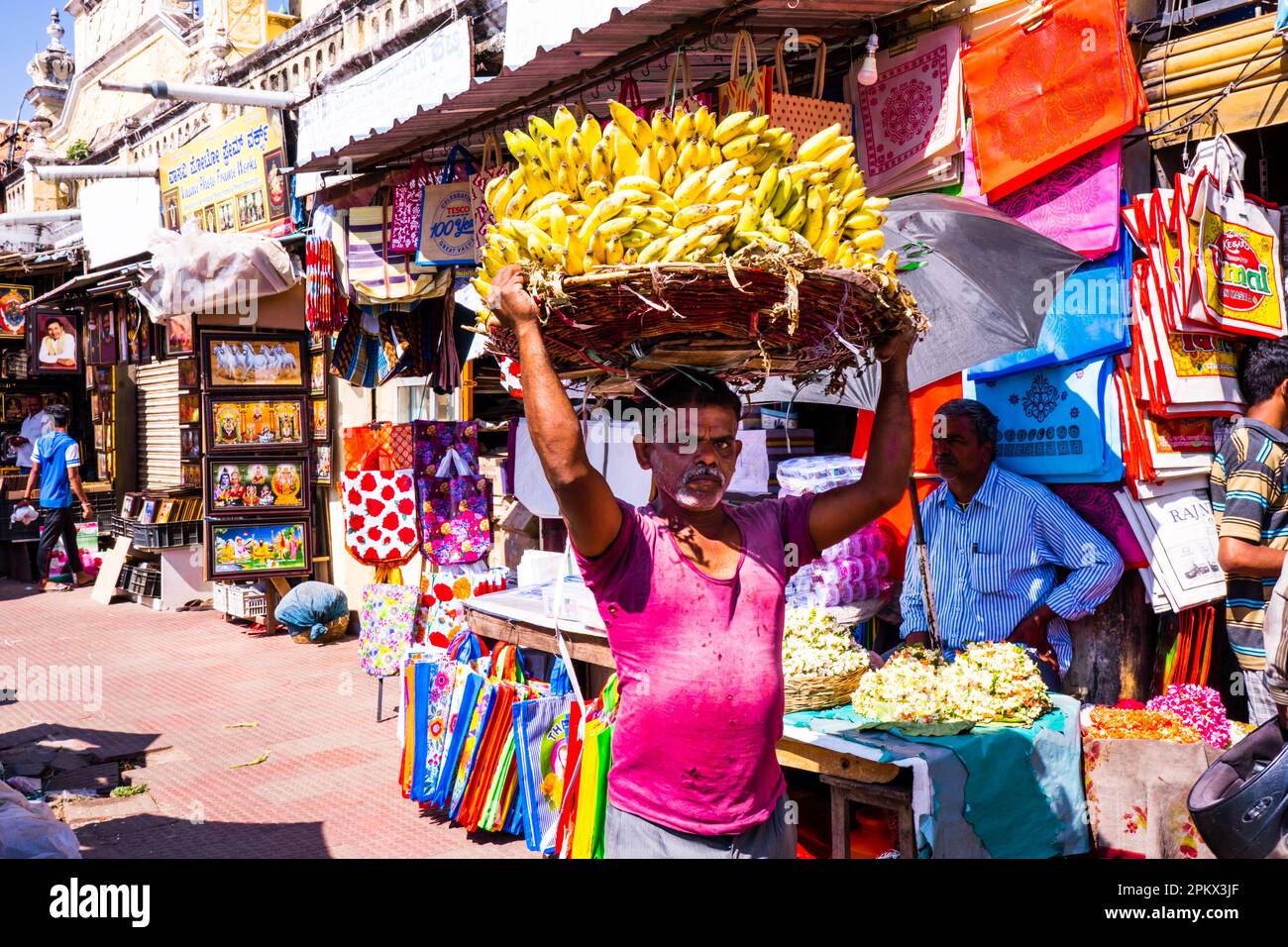 Mysore, Inde - 12.01.2023 : marché de Devaraja, marché traditionnel de rue Mysore, homme transportant des bananes dans un panier sur sa tête. Photo de haute qualité Banque D'Images