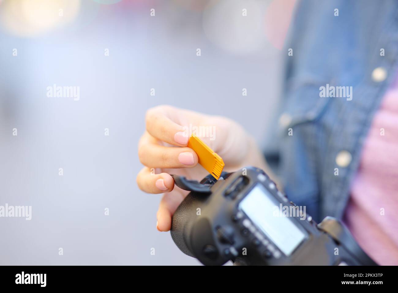 Gros plan d'un photographe qui insinait à la main une carte sd sur l'appareil photo dans la rue Banque D'Images