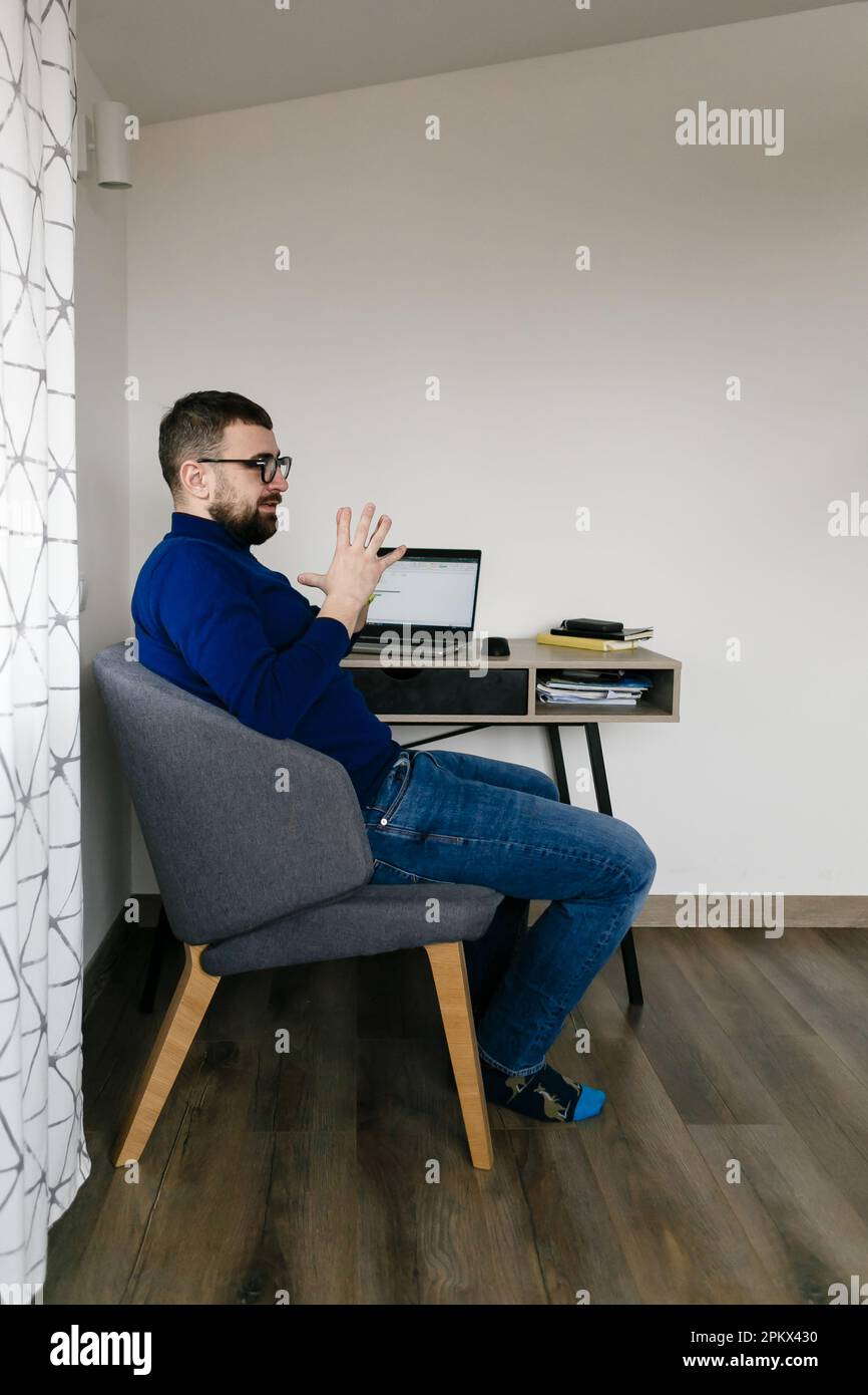 l'homme s'assoit à un bureau avec un ordinateur portable et des livres et pense à l'entreprise Banque D'Images
