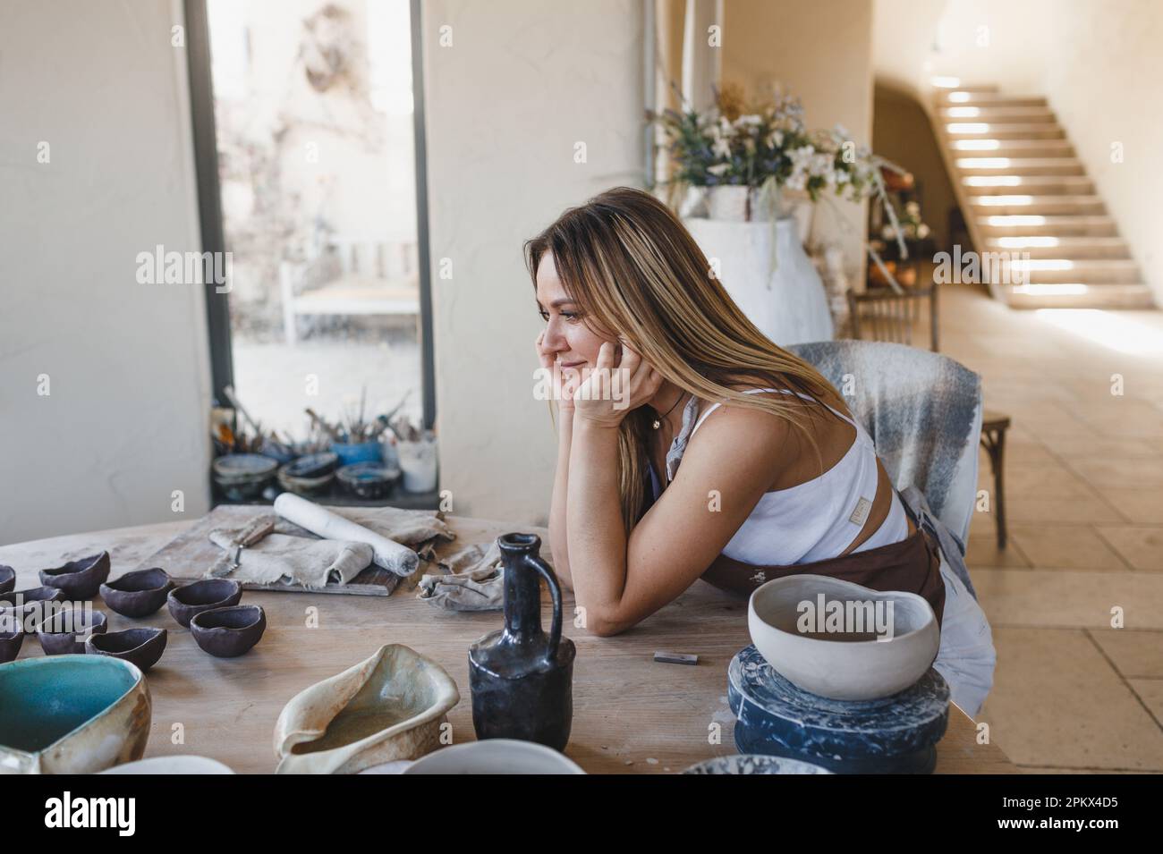 portrait d'une jeune fille céramiste assise à une table Banque D'Images