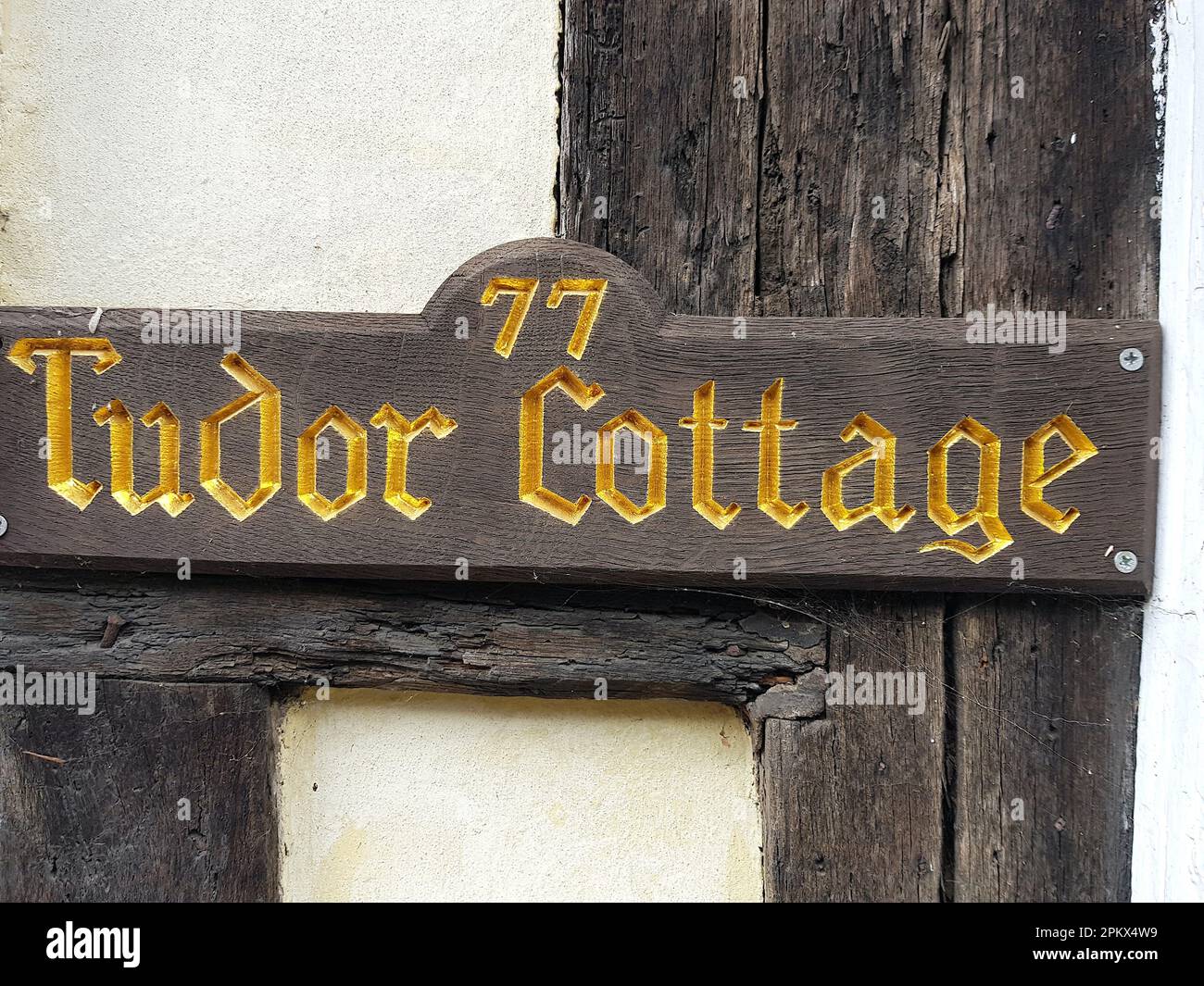 Le nom d'une maison en lettres sculptées d'or à l'ancienne sur une plaque de bois. Banque D'Images