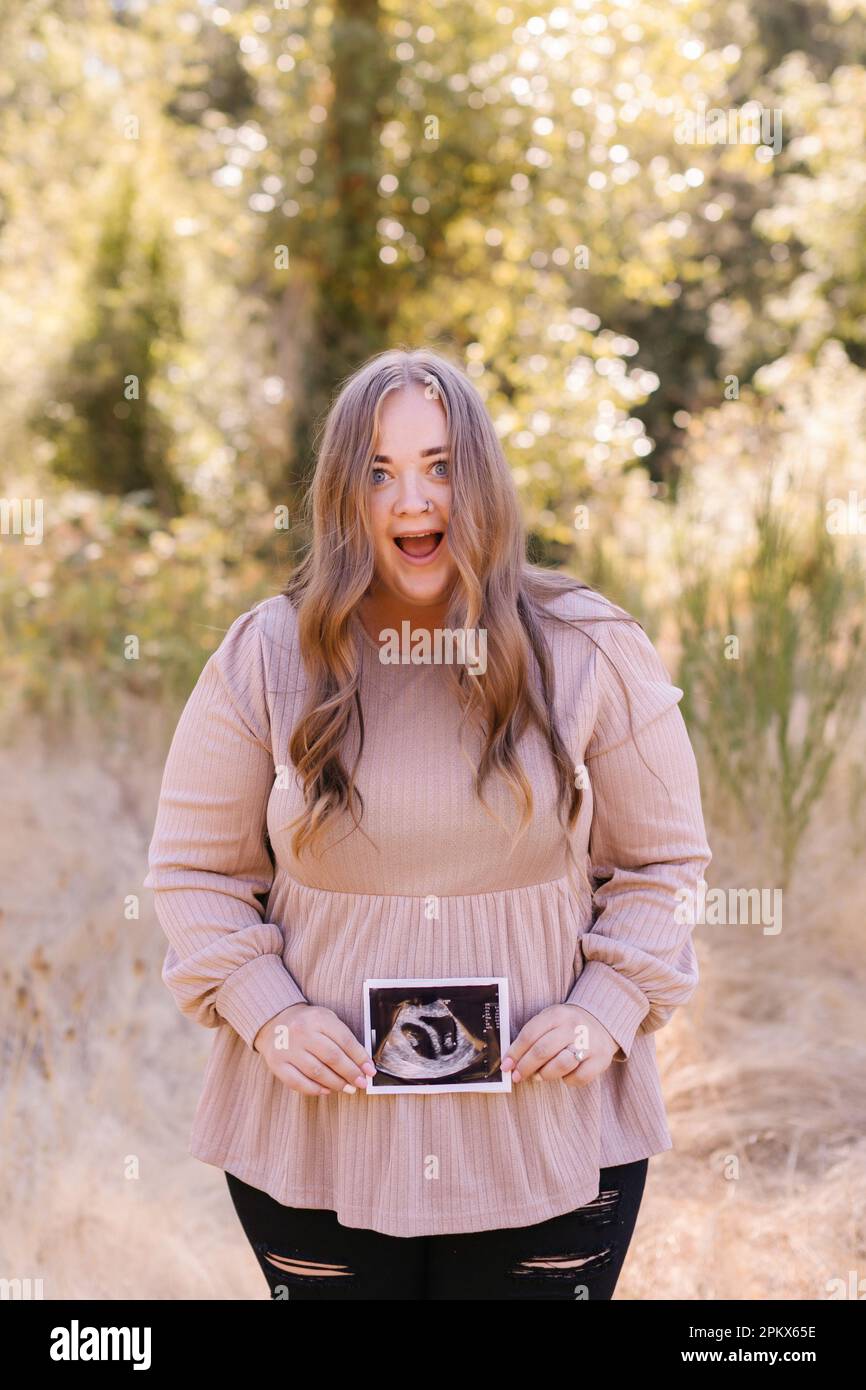 Mère enceinte choquée tenant une échographie de jumeaux Banque D'Images
