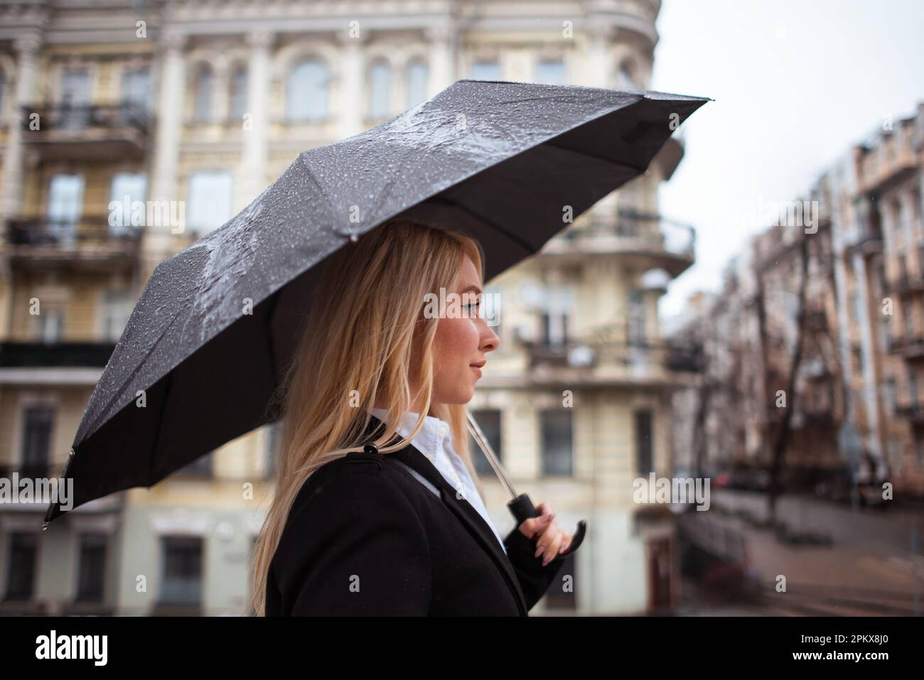 une jeune femme d'affaires se promenant dans la rue. la pluie tombe sur le grand  parapluie noir dans la main de femme Photo Stock - Alamy