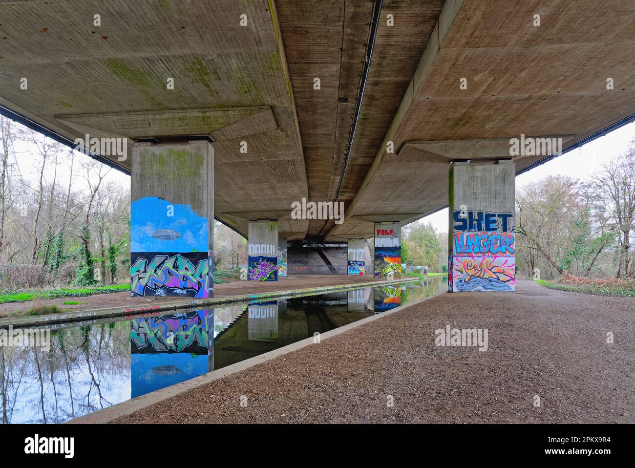 Graffiti peint sur des colonnes soutenant le pont de M25 qui le transporte au-dessus du canal de la rivière Wey à New Haw Surrey, Angleterre, Royaume-Uni Banque D'Images